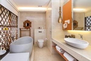 a bathroom with a white tub and a sink at MERUSAKA Nusa Dua in Nusa Dua