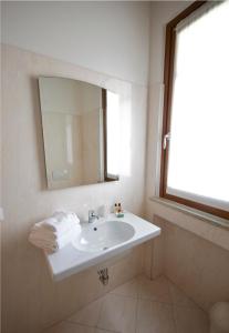 a white bathroom with a sink and a mirror at Suite Maria in Buttrio