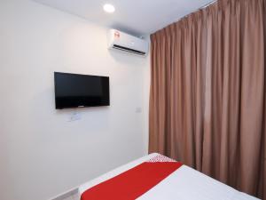 um quarto com uma cama e uma televisão na parede em OYO 1148 Kenyalang Suite em Miri