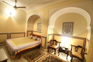 a bedroom with a bed and two chairs at Khatu Haveli in Jaipur