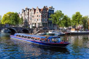 a boat on a river in front of buildings at Holiday Home Zeewolde in Zeewolde