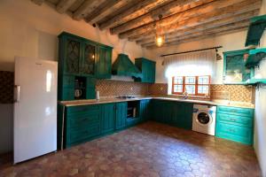 eine Küche mit grünen Schränken und einem weißen Kühlschrank in der Unterkunft Side Cottagehause in Side
