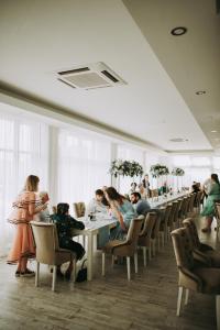 a group of people sitting at tables in a restaurant at Magnific Hotel in Borş