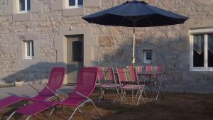een groep stoelen en een tafel met een paraplu bij Maison de Romagers in Aumont-Aubrac
