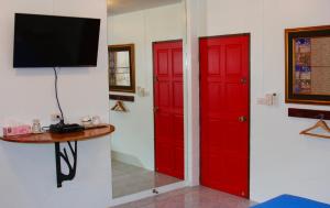 two red doors in a room with a tv at Tea Moon Beach House in Thongsala