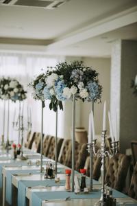 a row of tables with white and blue flowers on them at Magnific Hotel in Borş