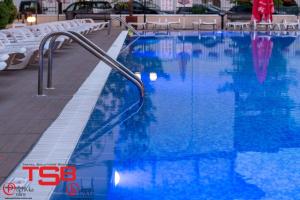 a swimming pool with blue water and white chairs at TSB Sunny Victory in Sunny Beach