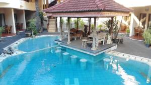 een zwembad met een prieel naast een huis bij The Flora Kuta Bali in Kuta