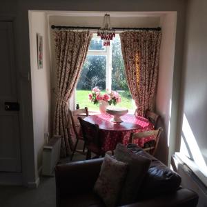 a living room with a table and a window at Pebble Cottage in Holt