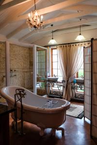 a large bath tub in a room with a balcony at Art Gallery Guest House in Haenertsburg