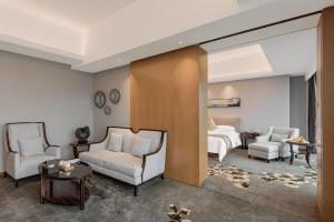 a hotel room with a bed and two chairs at Huaqiang Plaza Hotel Shenzhen, Enjoy Complimentary Mini Bar & Night Snack, Add breakfast - enjoy complimentary afternoon tea in Shenzhen