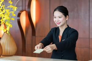 a woman sitting at a table holding a credit card at Huaqiang Plaza Hotel Shenzhen, Enjoy Complimentary Mini Bar & Night Snack, Add breakfast - enjoy complimentary afternoon tea in Shenzhen