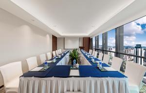 a long table with white chairs in a room with windows at Huaqiang Plaza Hotel Shenzhen, Enjoy Complimentary Mini Bar & Night Snack, Add breakfast - enjoy complimentary afternoon tea in Shenzhen