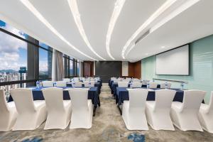 a conference room with tables and chairs and a screen at Huaqiang Plaza Hotel Shenzhen, Enjoy Complimentary Mini Bar & Night Snack, Add breakfast - enjoy complimentary afternoon tea in Shenzhen