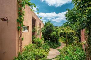 an alleyway between two buildings with plants at Somos in Nakijin