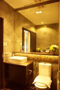a bathroom with a sink and a toilet and a mirror at Forest Crest Nature Hotel and Resort Powered by ASTON in Nasugbu