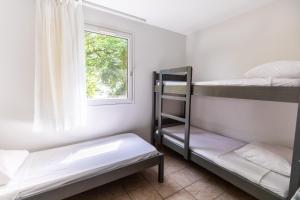 Cette chambre comprend 2 lits superposés et une fenêtre. dans l'établissement Village Beauséjour - Rêves de mer, au Conquet
