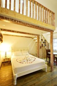 a bedroom with a white bed with a wooden floor at Real Maris Resort and Hotel in Boracay