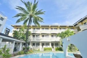 a large white building with a palm tree and a swimming pool at Real Maris Resort and Hotel in Boracay