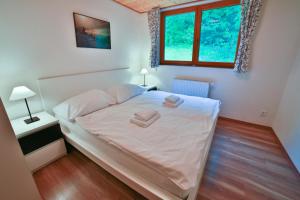 a bedroom with a bed with white sheets and two windows at Apartmány Maršíkov in Velké Losiny