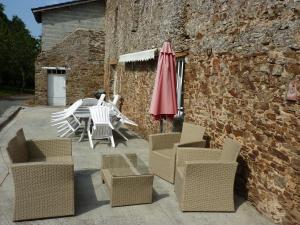 a patio with chairs and a table and an umbrella at B&B Chambres d'hôtes Ferme Mahyas in Saint-Jean-de-Savigny