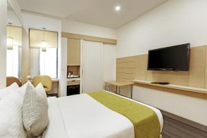 ein Hotelzimmer mit einem Bett und einem Flachbild-TV in der Unterkunft Sarovar Portico Outer Ring Road in Bangalore