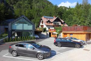 dois carros estacionados num parque de estacionamento em frente a um edifício em Vila Edelweiss Rooms&App Kranjska Gora em Kranjska Gora