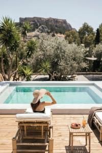 a woman sitting in a chair next to a swimming pool at Casita Casita Lindos - Adults Only in Líndos