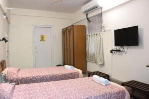 a room with two beds and a flat screen tv at YWCA International Centre in Mumbai