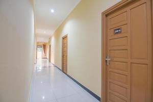 a hallway with a wooden door and a tile floor at RedDoorz Plus near Syamsudin Noor Airport 3 in Banjarbaru