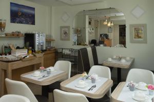 a restaurant with tables and chairs and a kitchen at Hôtel de Paris La Défense in Puteaux