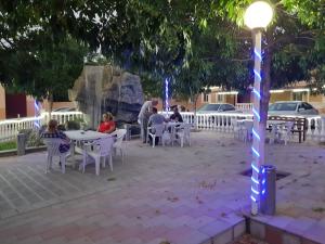 people sitting at tables in a park at night at Hotel Selika in Rustavi