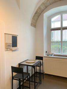 d'une salle à manger avec une table, des chaises et une fenêtre. dans l'établissement Wohnen in ehemaligen Kloster, à Lichtenfels