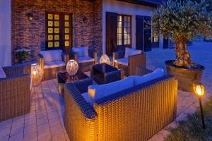 a patio with wicker chairs and tables with lights at Le Clos Magedon in Médan