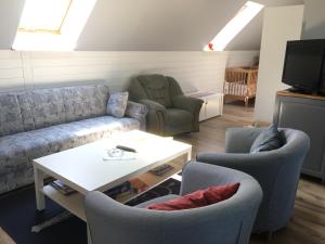 ein Wohnzimmer mit einer Couch, zwei Sesseln und einem Tisch in der Unterkunft Statarlängan in Visby