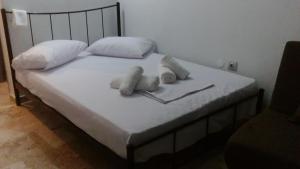 Una cama con sábanas blancas y almohadas. en agia marina riviera aigina, en Agia Marina Aegina