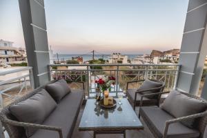 a balcony with two couches and a table with flowers at Stegna Bay Apartment in Archangelos