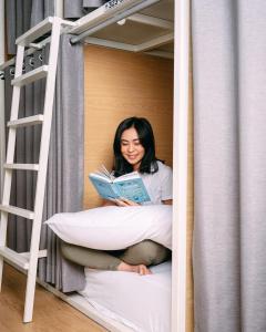 a woman sitting in a bunk bed reading a book at SO! Boutique Hostel in Malang