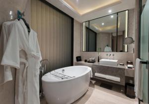 un bagno con vasca e un grande specchio di Pullman Shanghai Xuhui a Shanghai