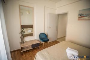 a bedroom with a blue chair and a mirror at Explore Greece from Close the Sea Apartment in Chalkida