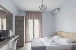 a white bedroom with a bed and a television at STRAWBERRY Skiathos in Agia Paraskevi