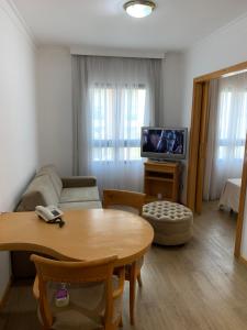 a living room with a couch and a table and a tv at Charmoso Flat em Pinheiros in Sao Paulo