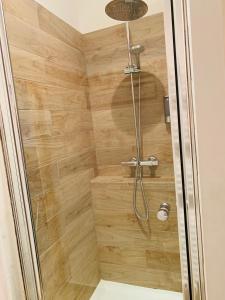 a shower with a wooden wall in a bathroom at Victoire Appartement in Aix-en-Provence