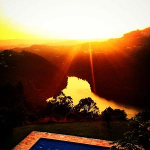 una puesta de sol sobre un cuerpo de agua con una piscina en Quinta das Tílias Douro Valley, en Cabaça
