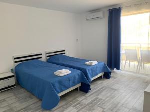 1 dormitorio con 2 camas con sábanas azules y ventana en Апартаменти Романтика Кирково en Kirkovo