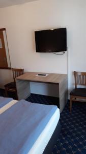 a hotel room with a desk with a flat screen tv at Hotel Elsenztal in Bammental