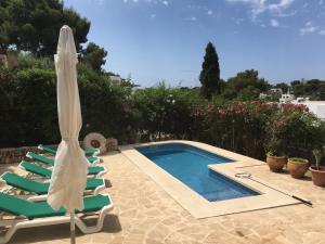 a swimming pool with lawn chairs and an umbrella at Villa Imperial in Cala d´Or
