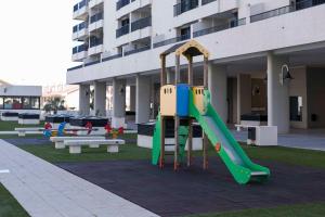 einen Spielplatz mit Rutsche vor einem Gebäude in der Unterkunft ApartUP Patacona Palm Beach I in Valencia