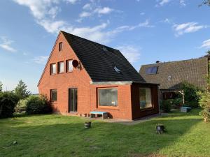 een rood bakstenen huis met een zwart dak bij Haus Plüschmors in Garding