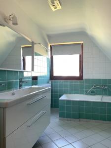 een badkamer met een wastafel, een bad en een raam bij Haus Plüschmors in Garding